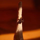 Tsugumi kintsugi cocktail ring with black enamel and gold crack lines in warm directional light.