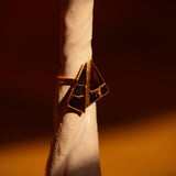 Side view of Tsugumi kintsugi ring showing geometric black enamel form with gold detailing in warm light.