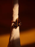 Side view of Tsugumi kintsugi ring showing geometric black enamel form with gold detailing in warm light.