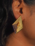 Vélora blue CZ geometric diamond statement earring in gold worn close to ear in profile shot.