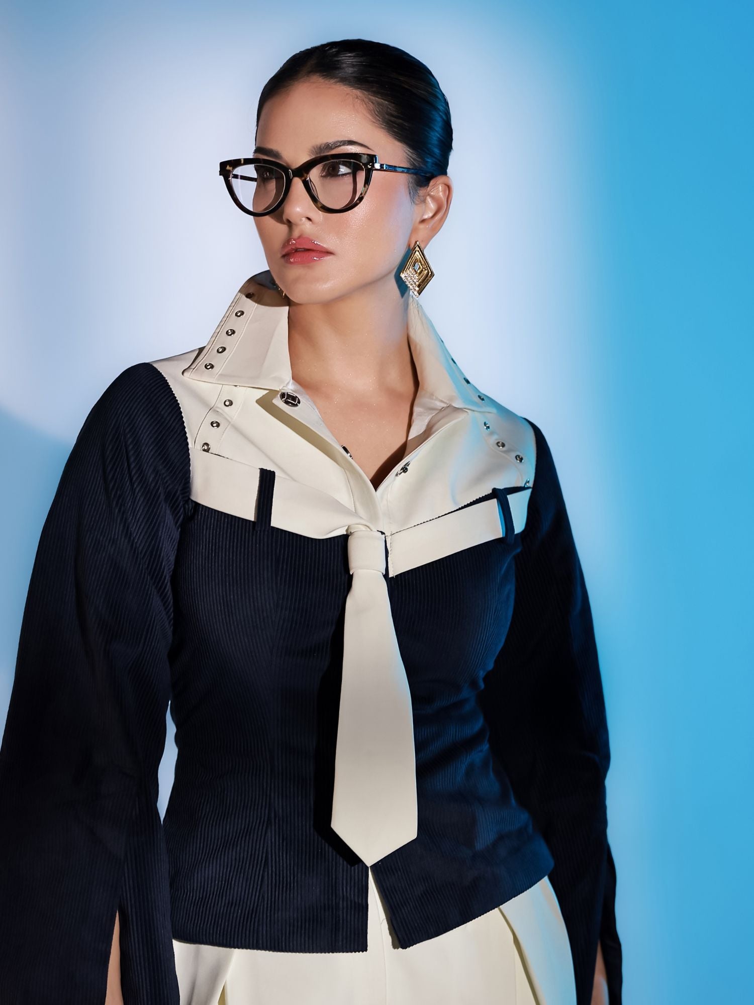 Model wearing gold Velora layered zircon earrings, front-facing portrait in blue light