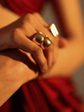 Model's hand wearing gold dome curve ring with chain bracelet in warm tones