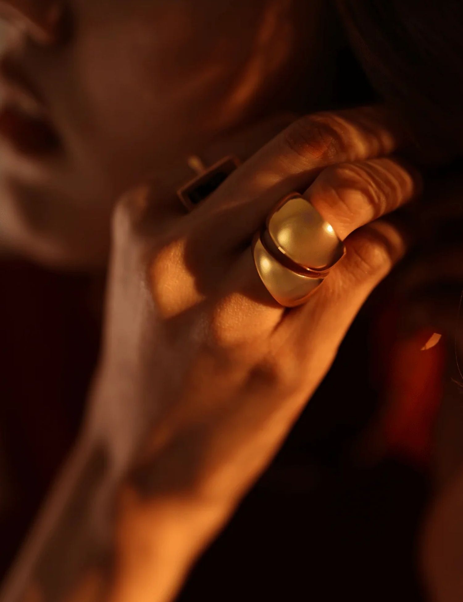 Model wearing bold gold dome curve ring, warm close-up on hand