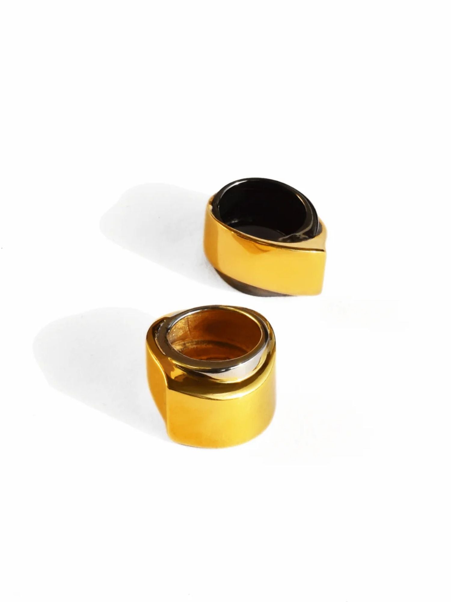 Angled shot of gold and black rhodium dual rings showing curved form
