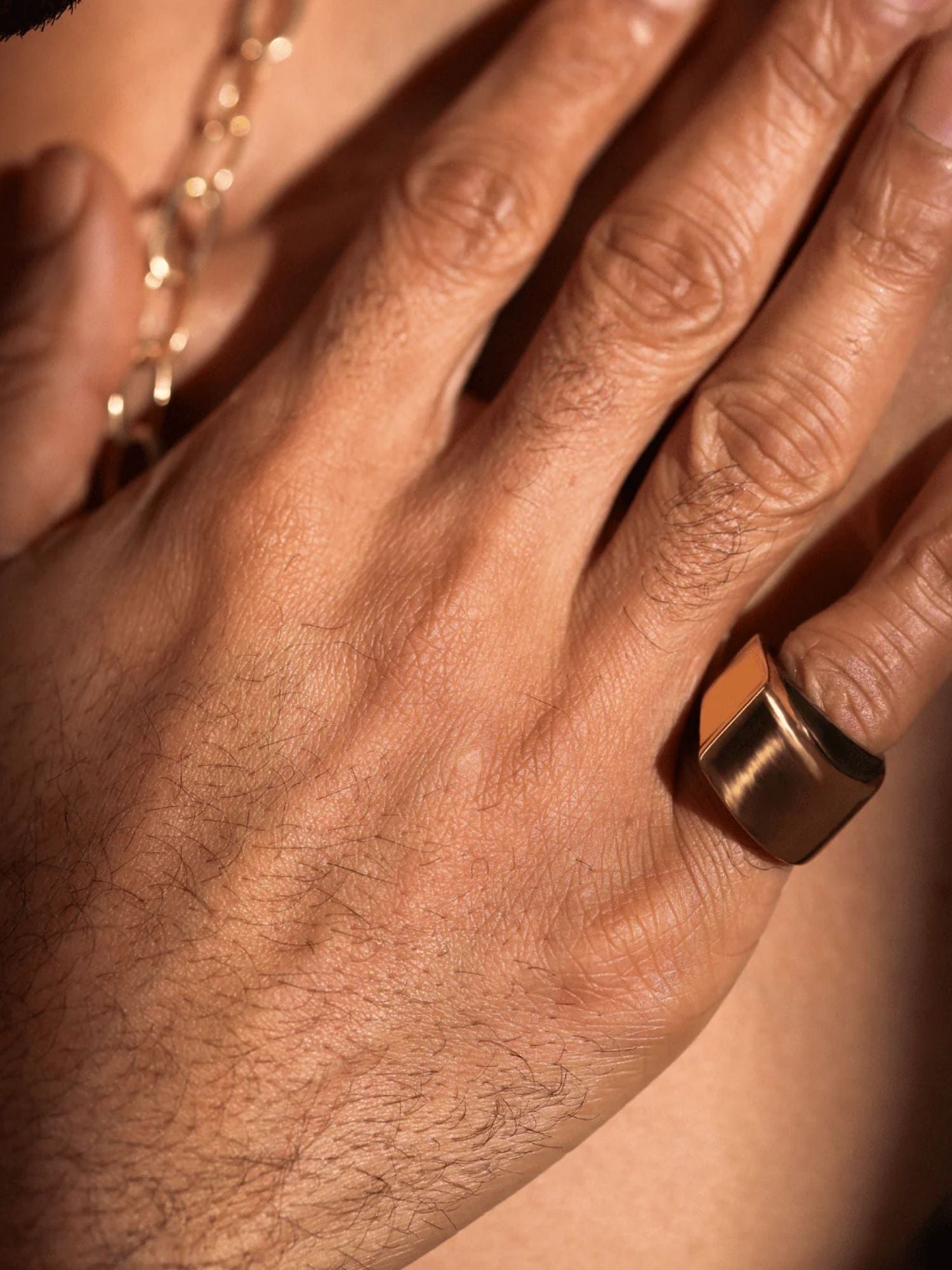 Close-up of gold dual ring on model's hand showing sculptural band width
