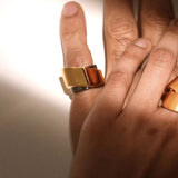 Model wearing two-tone gold dual ring on middle finger, warm light