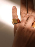 Model wearing two-tone gold dual ring on middle finger, warm light