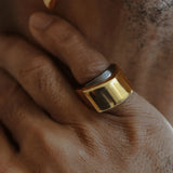 Model wearing dark grey and gold two-tone dual ring on hand in low light