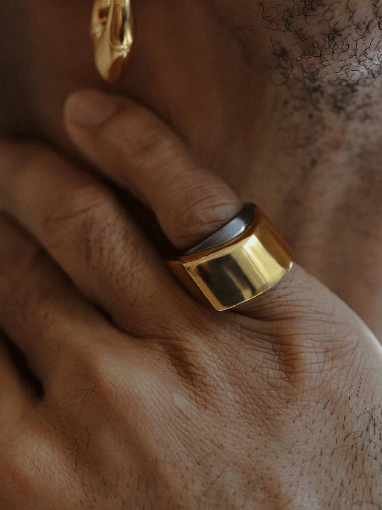 Model wearing dark grey and gold two-tone dual ring on hand in low light