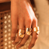 Model wearing gold ribbon ring stacked on multiple fingers