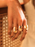 Model wearing gold ribbon ring stacked on multiple fingers